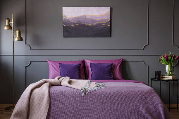 Elegant violet bedroom interior Pink blanket on violet bed in elegant bedroom interior with painting on grey molding wall lilac bedroom stock pictures, royalty-free photos & images