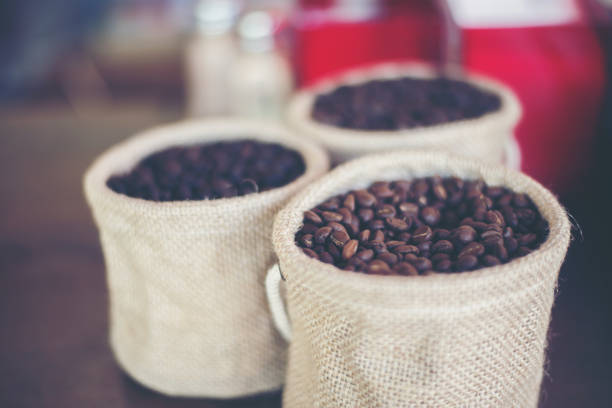 istock Sack of coffee beans on wooden background 957164496