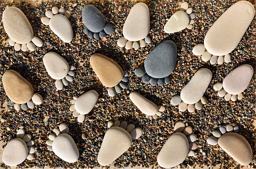 Pebble stones arranged like footprints on the beach. Family summer vacation concept