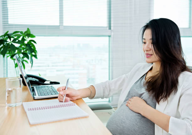 istock Pregnant woman writing in the office 957167552