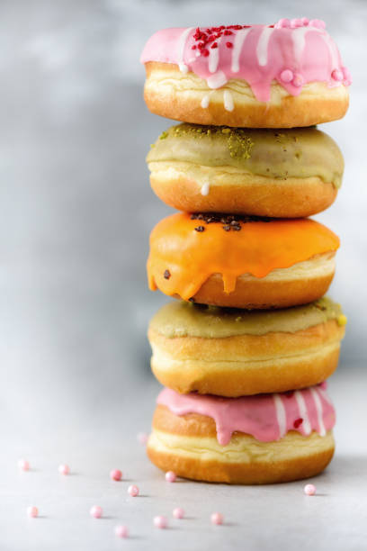istock Stack of glazed colorful assorted donuts with sprinkles on grey cement background. Copy space. Sweet doughnuts for kids 957167618