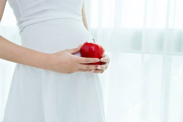 istock Pregnant woman holding a red apple 957168788