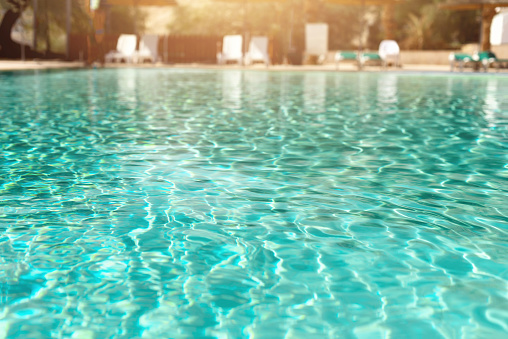 Tourist resort in the summer with woman walking next to swimming pool. 3D generated image. Generic location and architecture.