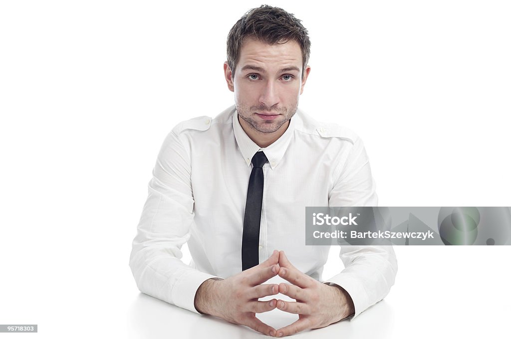 Giovane uomo d'affari seduto alla scrivania con grave viso - Foto stock royalty-free di Abbigliamento elegante