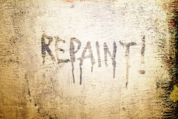 istock roughly painted wall closeup, white paint on dark background with repaint order on it 957184042