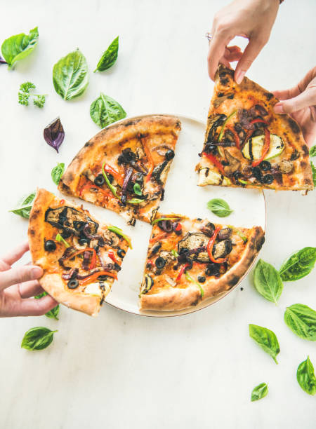 istock People's hands taking Freshly baked vegetarian pizza over marble background 957188568