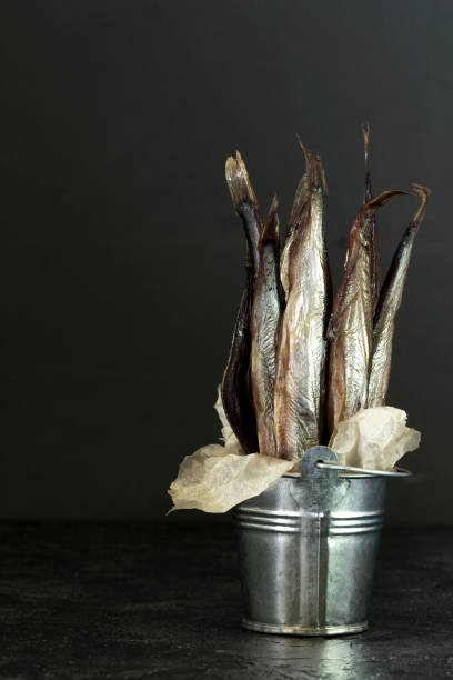 istock Capelin cold smoked fish in a decorative bucket on a dark background. 957193292