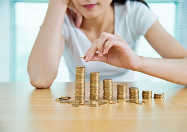 istock Woman putting a coin on stack of currency 957194330