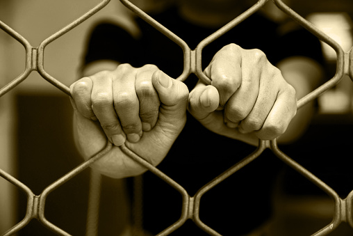 Close-up of woman hands on cell bars