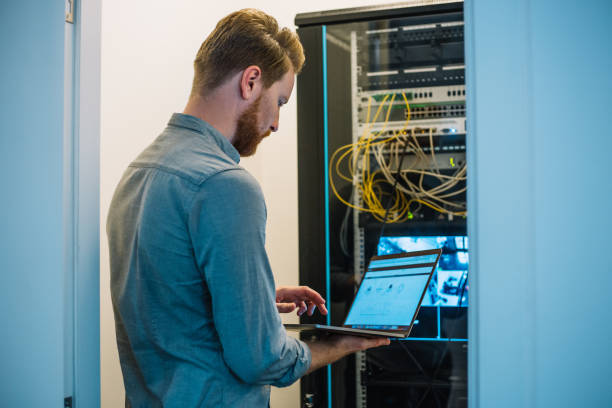 istock Male Caucasian IT technician using laptop in server room 957195428