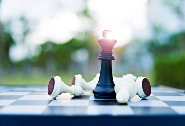 istock Black chess king among lying down white pawns 957202992