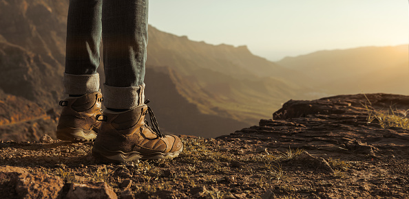 Close up of hikers boots enjoying the sunset on top of the mountain with copy space