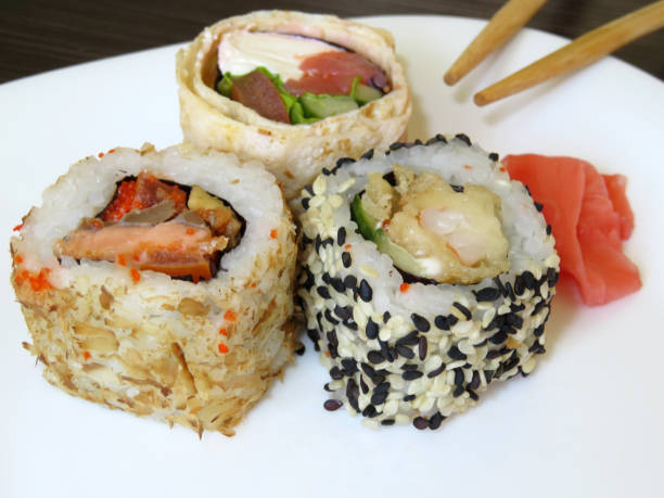istock Different kinds of Sushi rolls on white plate with chopsticks 957211792