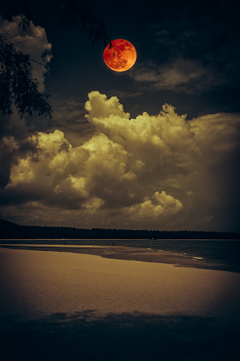 Beautiful landscape view on seascape to night. Attractive red full moon or blood moon on dark sky with cloudy. Serenity nature background. Vintage film filter effect. The moon taken with my camera.