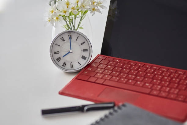 istock Close up of Clock,red tablet notebook and pen computer on white table. Selective focus 957224088