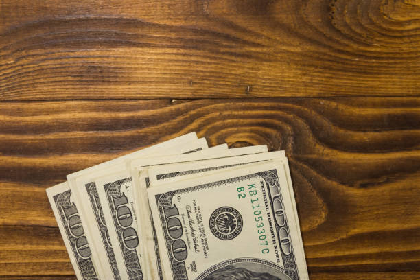 istock One hundred dollars bills on wooden desk 957224128