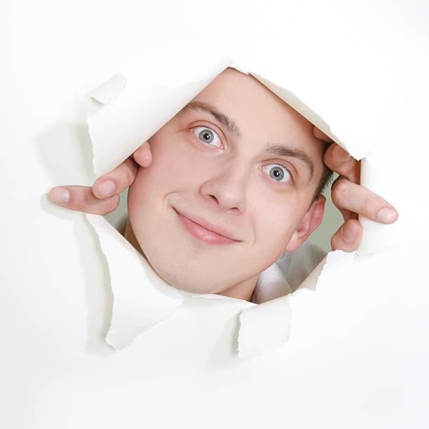 istock young man peeping through hole in paper 95723268