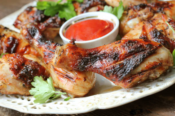 istock Grilled chicken legs on wooden table served on white plate with coriander 957234846