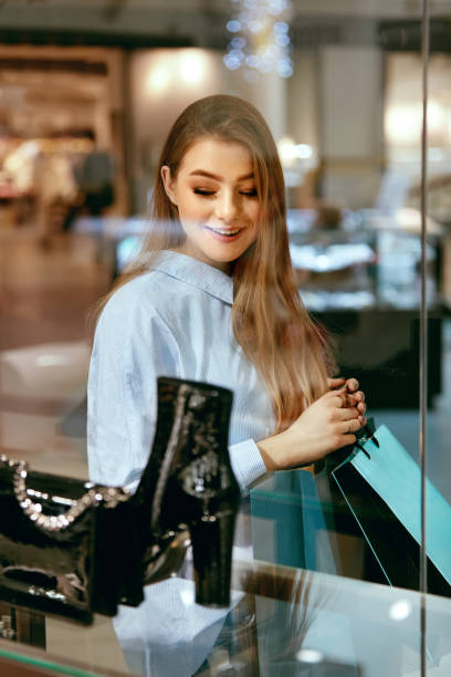 istock Young Woman Looking Through Shop Window 957239430