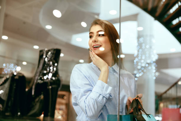istock Young Woman Looking Through Shop Window 957239618