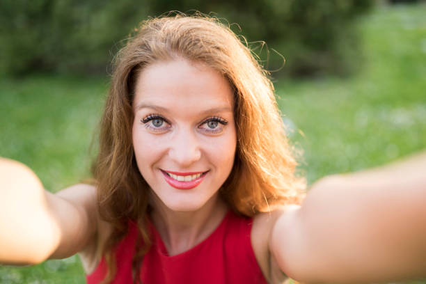 istock Beautiful lady in red taking a selfie 957239992