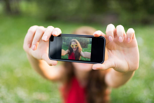 Lady taking a selfie in the park close-up stock photo