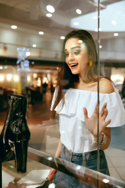 istock Young Woman Looking Through Shop Window 957245564