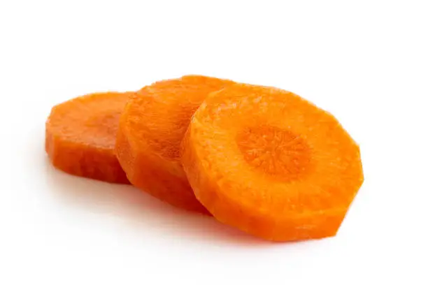 Three round slices of peeled carrot isolated on white.
