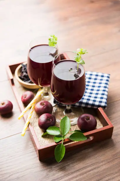 Photo of Kokum Sharbat, Juice or Sherbet OR summer coolant drink made up of Garcinia indica with raw fruit, served in a glass with mint leaf. selective focus