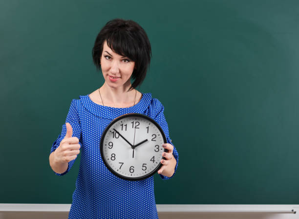 istock woman with big clock shows Okey gesture, chalk board background, time and education concept, green background, studio shot 957263036