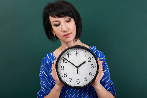 istock woman with big clock posing by chalk board, time and education concept, green background, studio shot 957263282