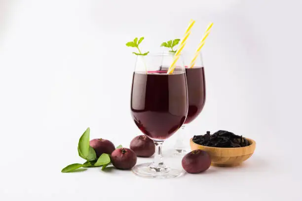 Photo of Kokum Sharbat, Juice or Sherbet OR summer coolant drink made up of Garcinia indica with raw fruit, served in a glass with mint leaf. selective focus