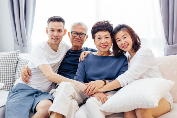 asian family with adult children and senior parents relaxing on a sofa at home together - grandmother senior adult child multi generation family imagens e fotografias de stock