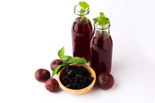 Photo of Kokum Sharbat, Juice or Sherbet OR summer coolant drink made up of Garcinia indica with raw fruit, served in a glass with mint leaf. selective focus