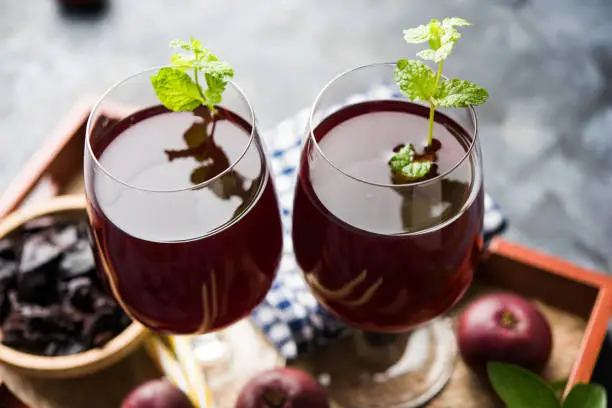 Photo of Kokum Sharbat, Juice or Sherbet OR summer coolant drink made up of Garcinia indica with raw fruit, served in a glass with mint leaf. selective focus