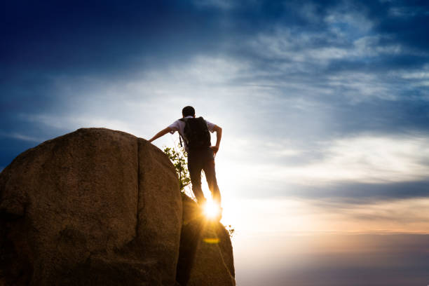 Hiker on top of mountain at sunset.