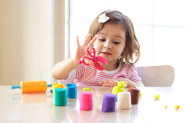 Toddler girl playing with playdough on kitchen counter stock photo