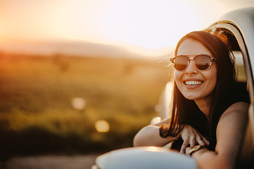 Cute young woman hanging her head from a car