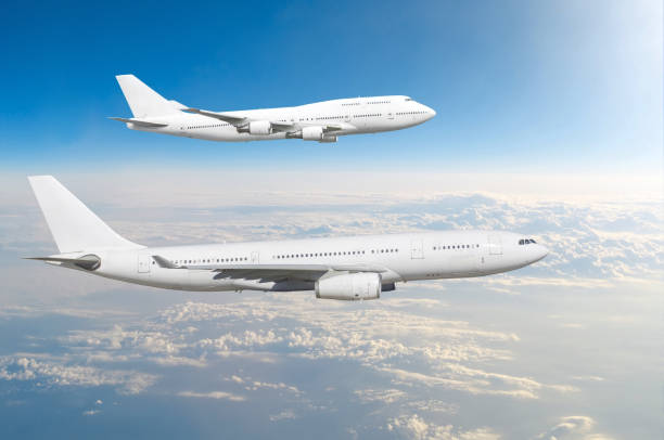 istock Two large white passenger airplanes fly parallel to each other in the sky above the clouds. 957288954