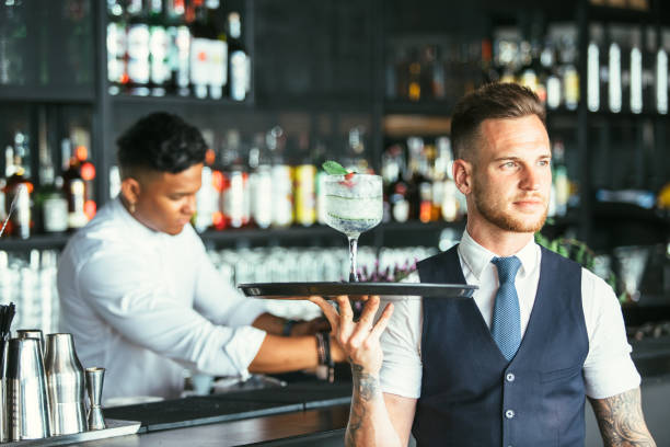 istock Elegant waiter serving a cocktail 957289100