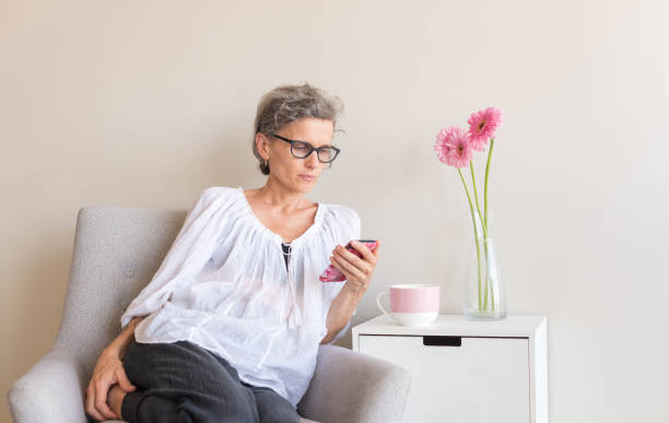 istock Middle aged woman in glasses using smart phone 957294298