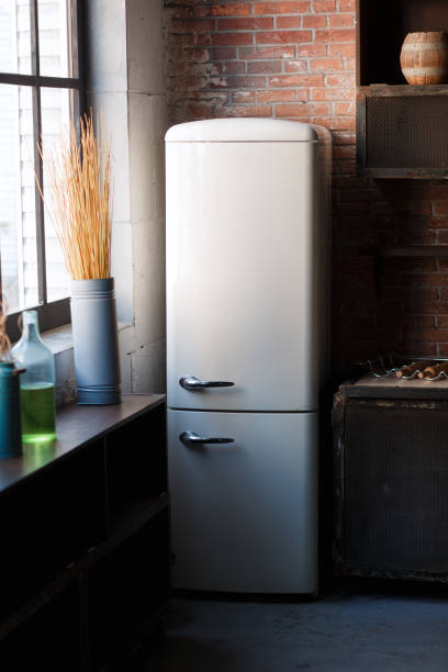 istock Kitchen interior in dark textured colors with white modern retro fridge, rustic brick wall, window and vase decor. Vertical still-life photo 957294840