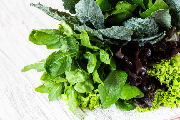 istock Leaves of green and red lettuce, rucola, kale, amaranth, spinach on white table 957297720