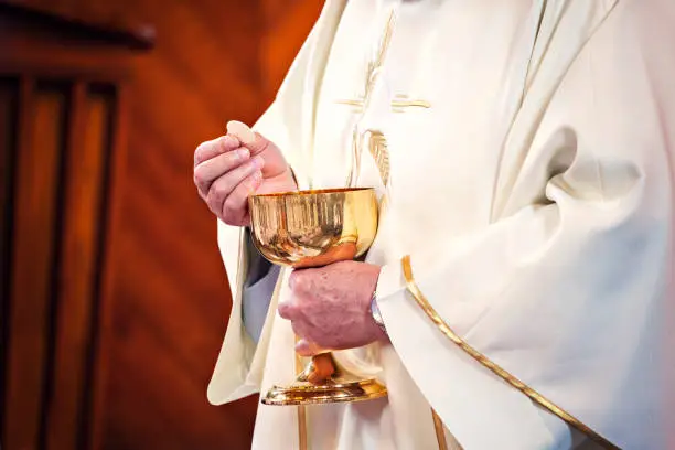 Communion and clergyman. Priest holds Holy Communion in his hands. Priest gives the Body of Christ during the First Holy Communion