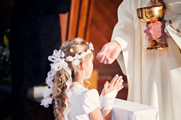 Communion and clergyman. Priest holds Holy Communion in his hands. Priest gives the Body of Christ during the First Holy Communion