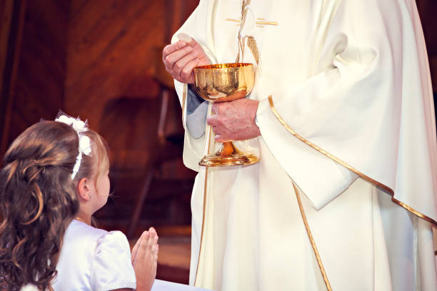 istock Communion and clergyman. First Holy Communion. 957298948