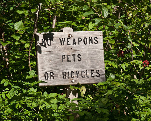 Trail Sign for Weapons, Pets and Bicycles In order to preserve their wild qualities, designated national wilderness areas are restricted as to use. Generally this means that no mechanical or motorized transportation is allowed. Only foot and equestrian travel are permitted. This sign was photographed on the Cascade Pass Trail in North Cascades National Park Wilderness near Marblemount, Washington State, USA. jeff goulden north cascades national park stock pictures, royalty-free photos & images