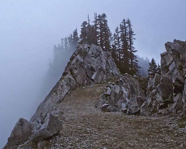 Kendall Katwalk on the Pacific Crest Trail Kendall Katwalk is a high narrow ridge on the Pacific Crest Trail. In this picture the trail was photographed on a foggy day. The view can be spectacular on a clear day. Kendall Katwalk is in the Alpine Lakes Wilderness of Washington State, USA. jeff goulden alpine lakes wilderness stock pictures, royalty-free photos & images