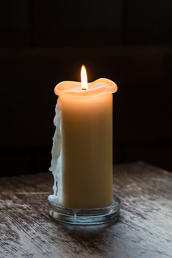 A lit cream candle with wax running down its side