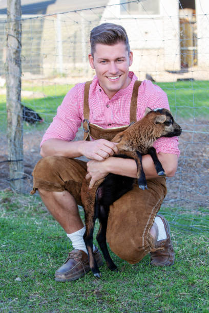 istock blond bavarian man holding a little goat 957328972
